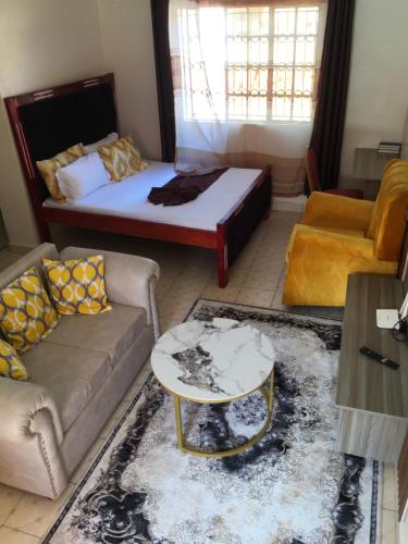 a living room with a bed and a couch and a table at Kristina Gardens 1BD & Studio Homes in Voi