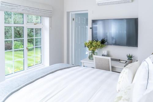 a white bedroom with a bed and a tv at Monkey Island Estate - Small Luxury Hotels of the World in Windsor