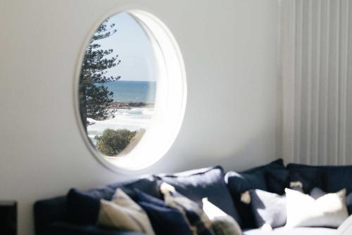 a living room with a couch and a round mirror at La Ronde Three - Unit 3 - Oceanstays in Yamba