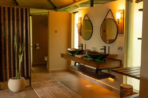 a bathroom with two sinks and two mirrors on the wall at Surana Mara Camp in Mara Simba