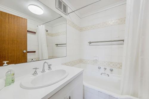 a white bathroom with a sink and a tub at Akuna 14, 6 Joffre Street in Port Macquarie