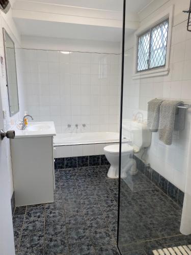 a bathroom with a tub and a toilet and a sink at Allamanda House, 3 Willow Street in Crescent Head
