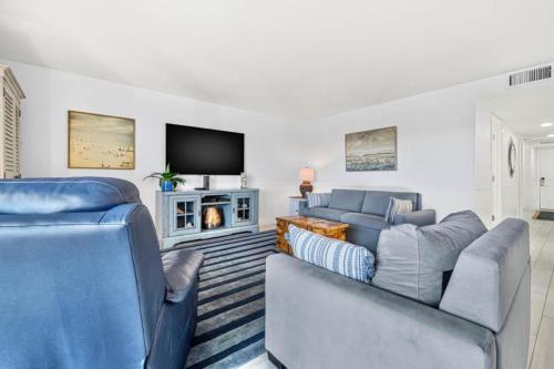 a living room with two blue couches and a tv at Escape to Beach Oasis! Family Friendly, Updated Beachside Condo with Heated Pool! in Clearwater Beach