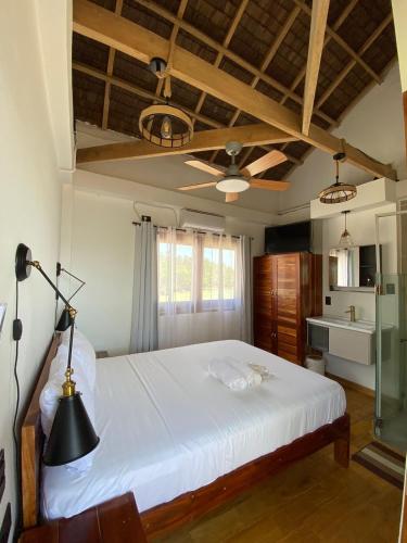 a bedroom with a large white bed with a ceiling at Hydrogen Beach Bar and Resort in San Francisco