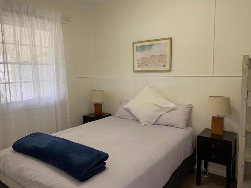 a bed with a blue pillow on it in a bedroom at Fleur Cottage, 7 Willow Street in Crescent Head