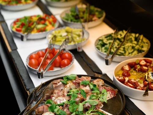 a table with many different plates of food on it at Mercure Budapest Korona in Budapest