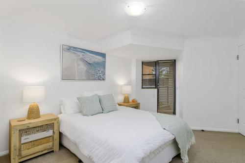 a white bedroom with a bed and a window at Flightdeck 101, Clarence Street in Port Macquarie