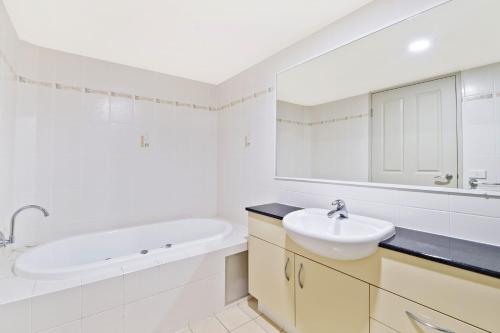 a white bathroom with a sink and a bath tub at Flightdeck 301, Clarence Street in Port Macquarie