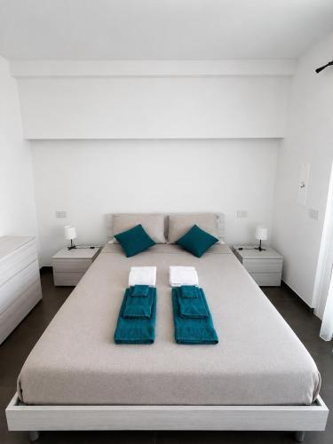 a white bedroom with a large bed with blue pillows at Appartamento Leon in Roseto degli Abruzzi