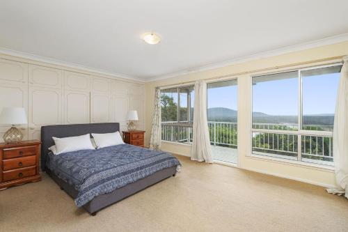 a bedroom with a bed and large windows at La Mer, 19 Dulconghi Street in Crescent Head