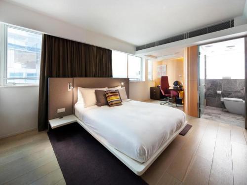 a bedroom with a large bed and a bathroom at Ovolo Central in Hong Kong