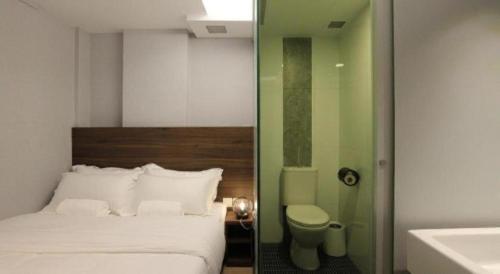 a bedroom with a bed and a toilet and a sink at ST Signature Bugis Beach in Singapore