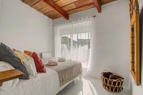 a white bedroom with a bed and a window at La Paredita Casa Acentejo in Tanque