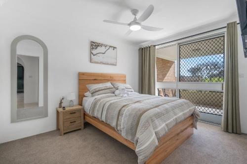 a bedroom with a bed and a mirror and a window at Relax at Flynn s View in Port Macquarie
