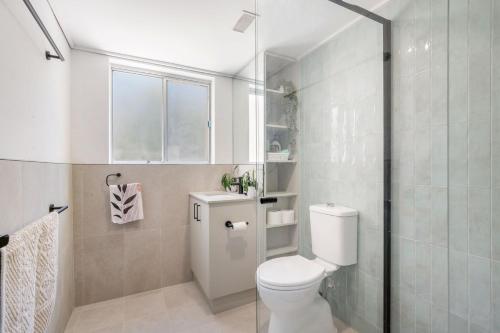 a bathroom with a toilet and a glass shower at Relax at Flynn s View in Port Macquarie