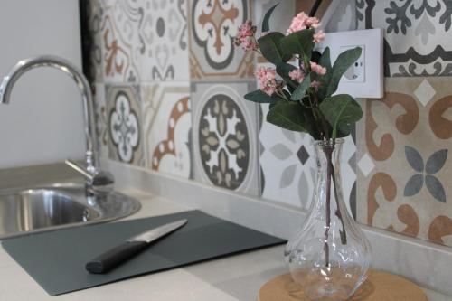 a vase of flowers on a counter with a knife at Los Llanos Loft & Suites in Manzanilla