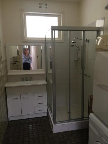 a woman taking a picture of a shower in a bathroom at Rosemaree, 24 East Street in Crescent Head