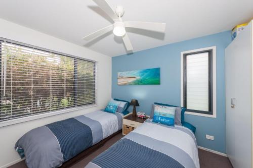 two beds in a bedroom with blue walls and a window at Sandy Shores, Serenity Resort in Diamond Beach
