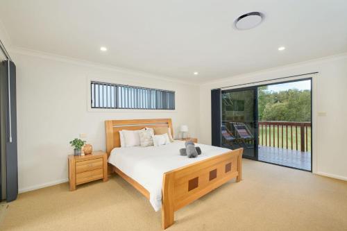a bedroom with a large bed and a balcony at Riverside Luxury in Port Macquarie