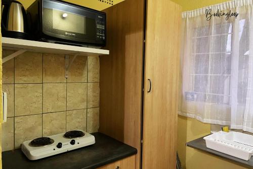 a small kitchen with a microwave and a stove at Budget Stays at Olivia Pines Guesthouse in Krugersdorp