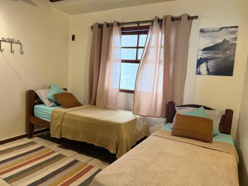 two beds in a room with a window at Duplex 450m da Praia do Peró, Roupa Cama e Banho, Wi-Fi, TV a Cabo, Estacionamento in Cabo Frio