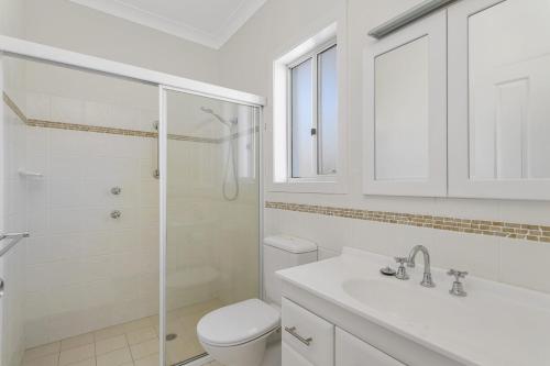 a white bathroom with a toilet and a shower at Vaka Malua, 7 Scott Street in Crescent Head