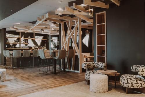 a room with a bar with chairs and tables at Aktiv & Spa Hotel Alpenrose in Schruns