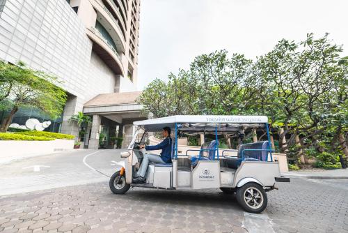 a man driving a golf cart on a street at Somerset Park Suanplu Bangkok in Bangkok