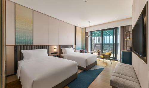 a hotel room with two beds and a tv at voco Kuching by IHG in Kuching