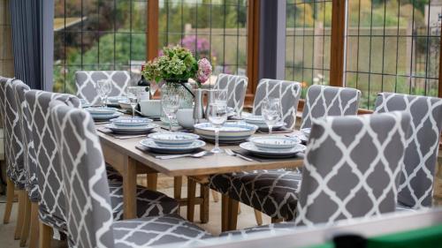 a wooden table with chairs and a vase of flowers at Kingfisher Cottage in Winchcombe