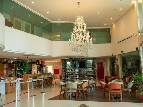 a restaurant with a chandelier and tables and chairs at ibis Vitoria da Conquista in Vitória da Conquista