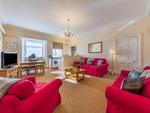 a living room with red couches and a table at The Garden Apartment - Uk48320 in Berwick-Upon-Tweed