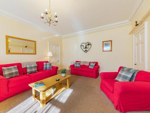 a living room with two red couches and a table at The Garden Apartment - Uk48320 in Berwick-Upon-Tweed