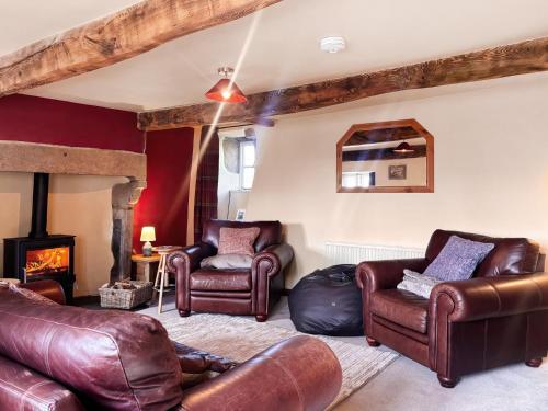 a living room with leather furniture and a fireplace at Holme House in Halton Gill