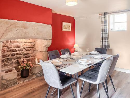 a dining room with a table and chairs and a stone fireplace at Holme House in Halton Gill