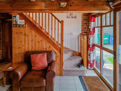 a living room with a leather couch and a staircase at Gull Newk in Flamborough