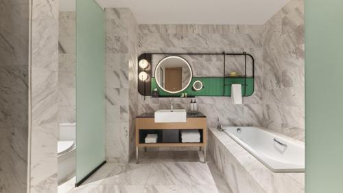 a bathroom with a tub and a sink and a mirror at voco Kuching by IHG in Kuching