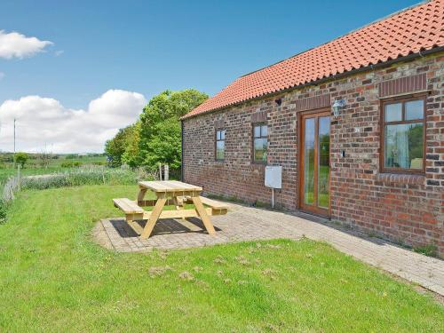 a wooden picnic table in front of a brick building at Meadow Cottage - Uk45882 in Flamborough