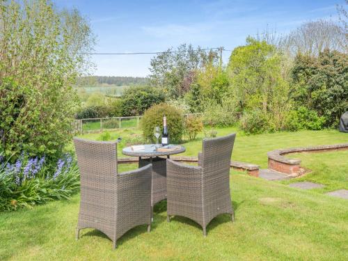a garden with a table and chairs in the grass at Hazel Cottage in Tolpuddle