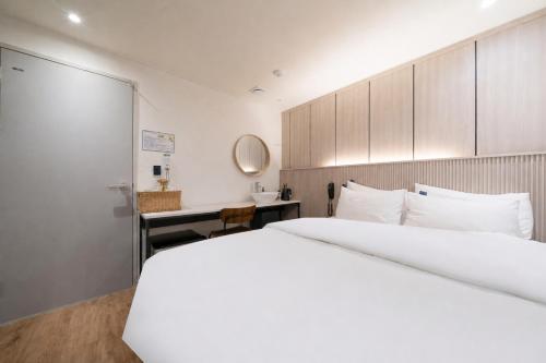 a bedroom with a large white bed and a desk at Just Stay Hotel in Seoul
