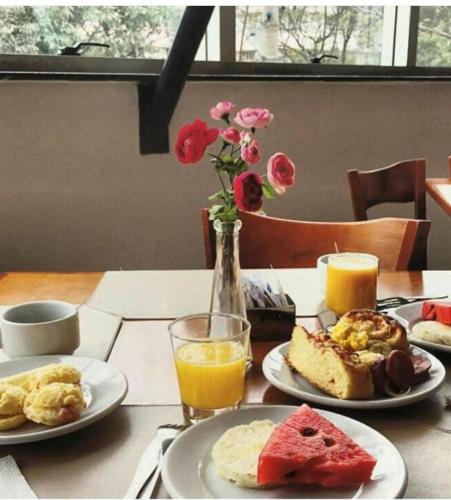a table with plates of breakfast food and a vase of flowers at Via Contorno Hotel in Belo Horizonte