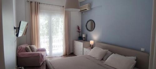 a bedroom with a bed and a chair and a window at Loutraki by the sea in Loutraki