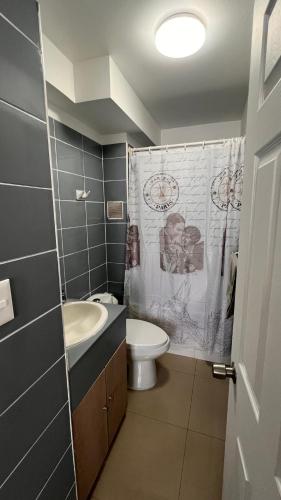 a bathroom with a sink and a toilet and a shower curtain at Departamentos Alpro Cavancha Vista a la Playa in Iquique