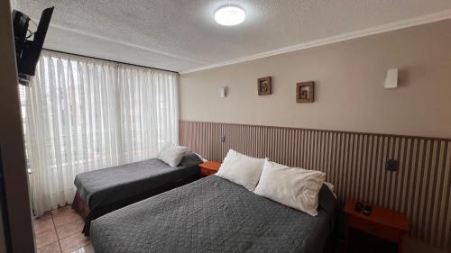 a hotel room with two beds and a window at Departamentos Alpro Cavancha Vista a la Playa in Iquique