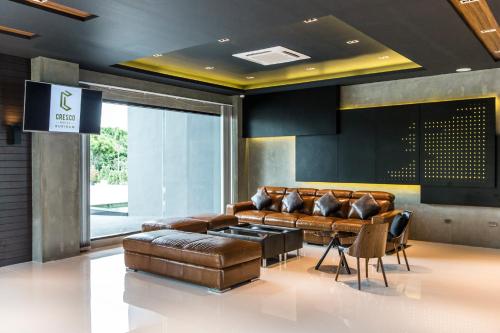 a lobby with a leather couch and a tv at Cresco Hotel Buriram in Buriram