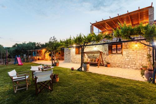a brick house with a table and chairs in a yard at Petalidi Olive Garden Stone House near the beach in Petalidi
