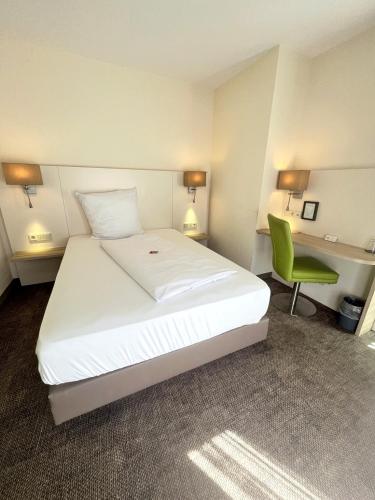 a bedroom with a bed and a desk and a green chair at Hotel-Restaurant Krüger in Grafhorst