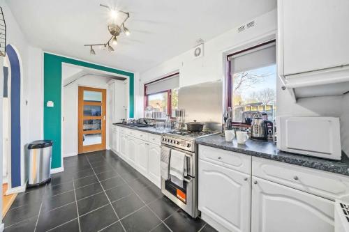 a large kitchen with white cabinets and appliances at Spacious 3BED Home in Rugby - Ideal for Groups in Clifton upon Dunsmore