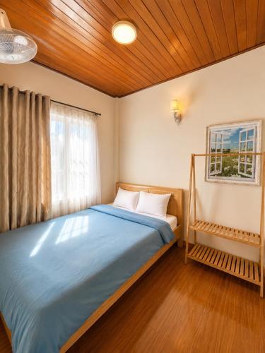 a bedroom with a blue bed with a window at Nhà Của Thỏ Vân Anh in Da Lat