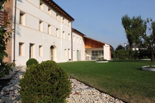 un grand bâtiment blanc avec une pelouse dans l'établissement Caspineda Agriturismo, à Montebelluna